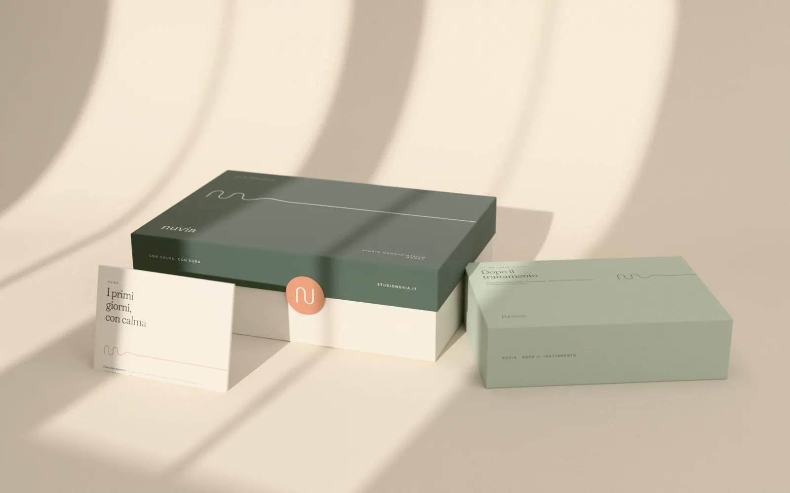 Kit di benvenuto Nuvia in scatola rigida verde salvia e avorio con sigillo color argilla, kit per i primi giorni dopo il trattamento in verde nebbia e guida stampata appoggiata alla scatola