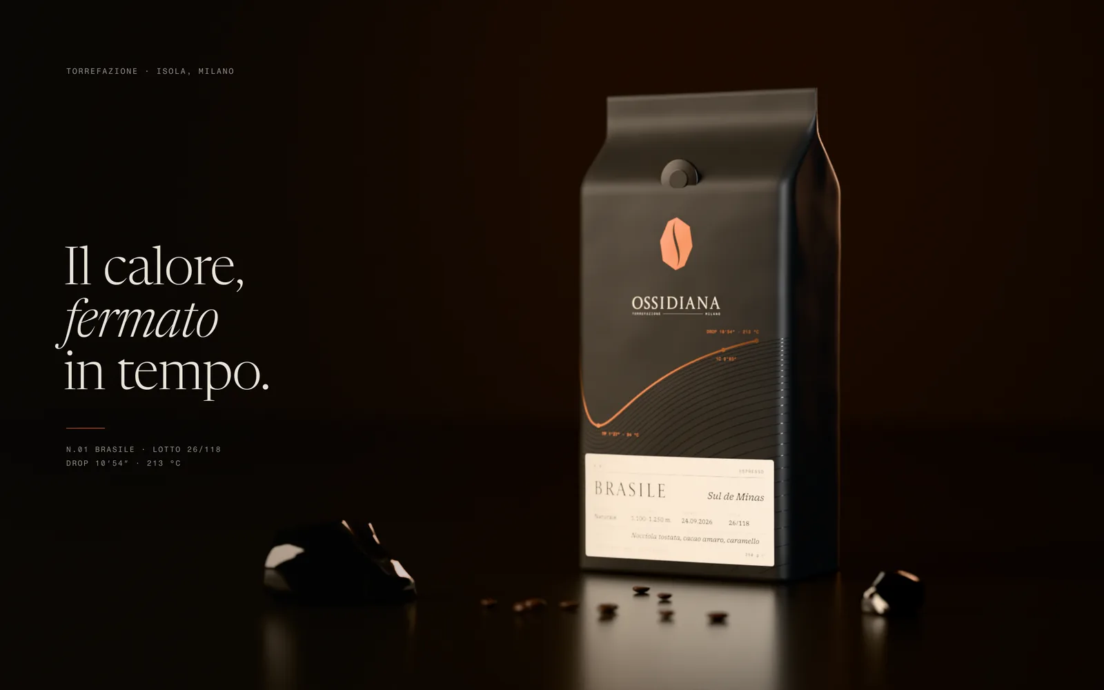 Sacchetto nero da 250 g di Ossidiana su pietra nera lucida, con il marchio a chicco sfaccettato in lamina rame, la curva di tostatura del lotto e l’etichetta crema «Brasile»; accanto schegge di ossidiana e chicchi di caffè, a sinistra il claim «Il calore, fermato in tempo.»